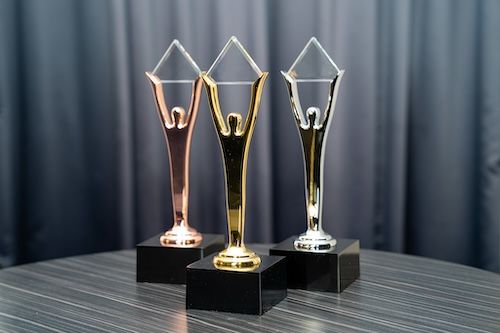 Bronze, Gold and Silver Stevie Award trophies on black bases, each a figure with arms raised holding a crystal diamond